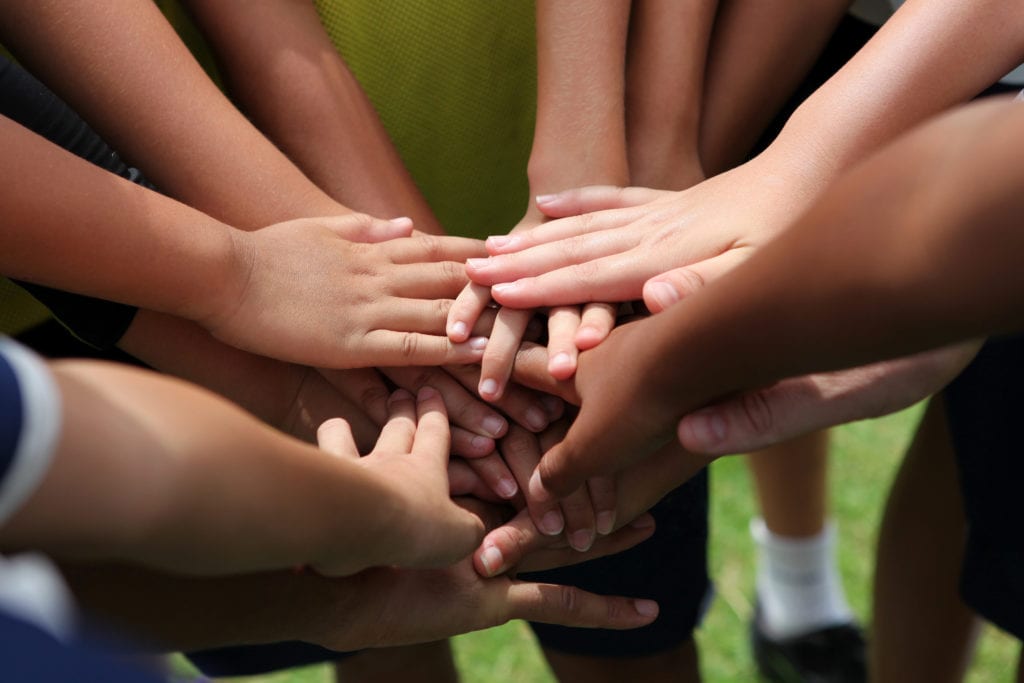 photo of children's hands together as if to say "on three: one, two, three!"