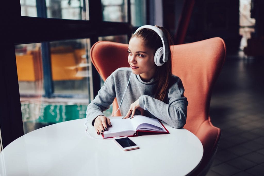girl with headphones on reading about music appreciation through the VLACS online program