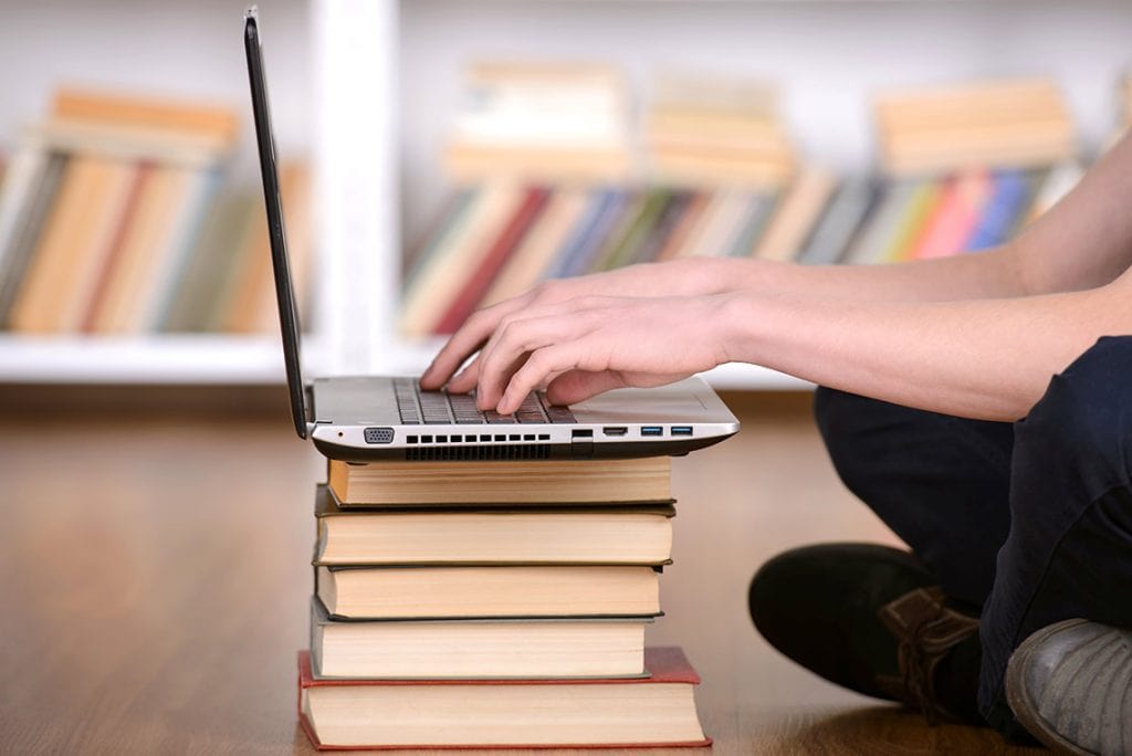 a laptop on top of a stack of books to signify the courses through which students can learn