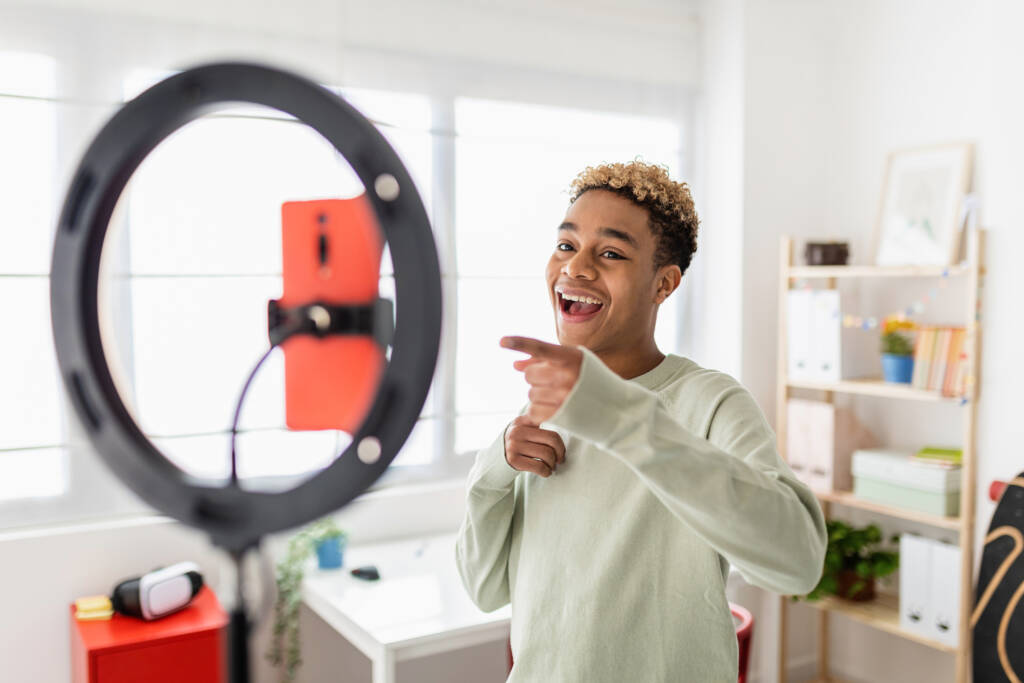 Young male creator recording online media video on his room - Millennial guy streaming online and sharing social media content by mobile phone app network