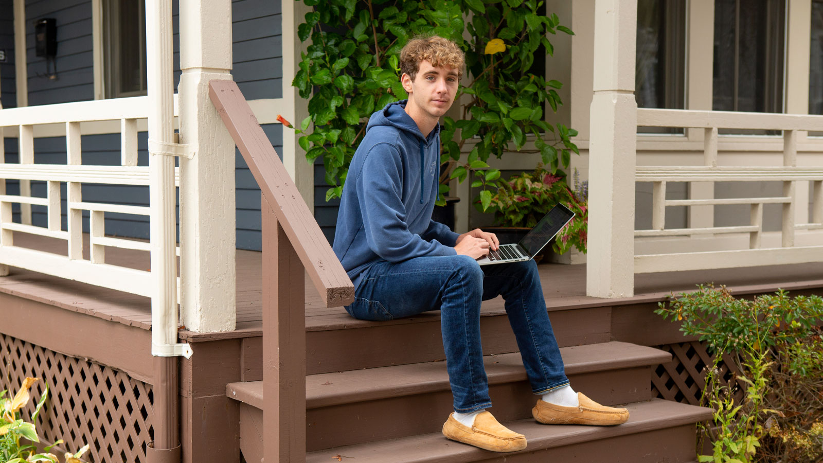 high school boy on laptop on his front porch