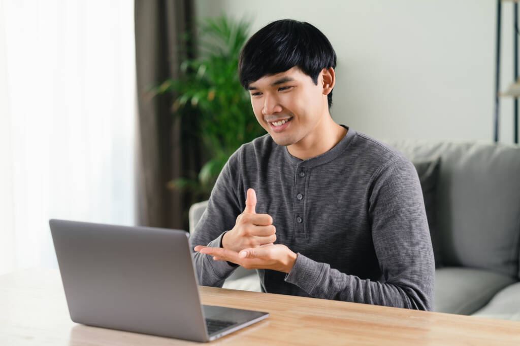 man sitting in front of laptop doing sign language
