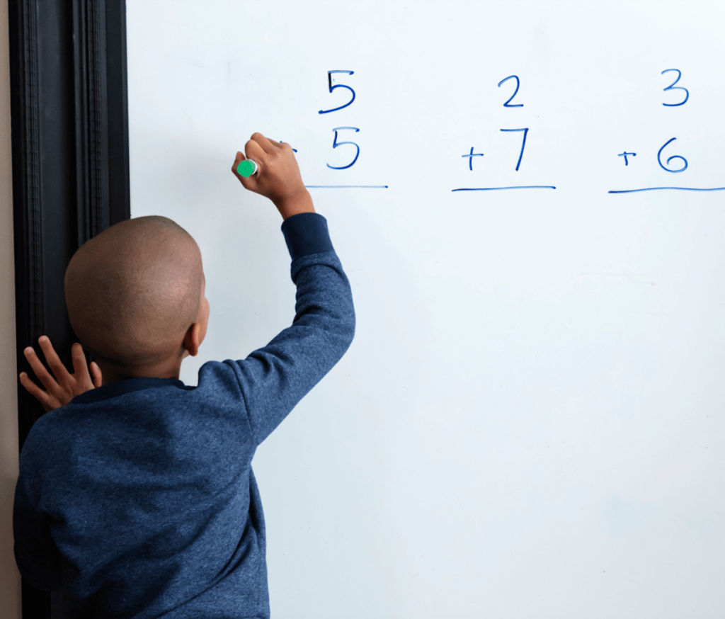 boy writing additional problems on white board
