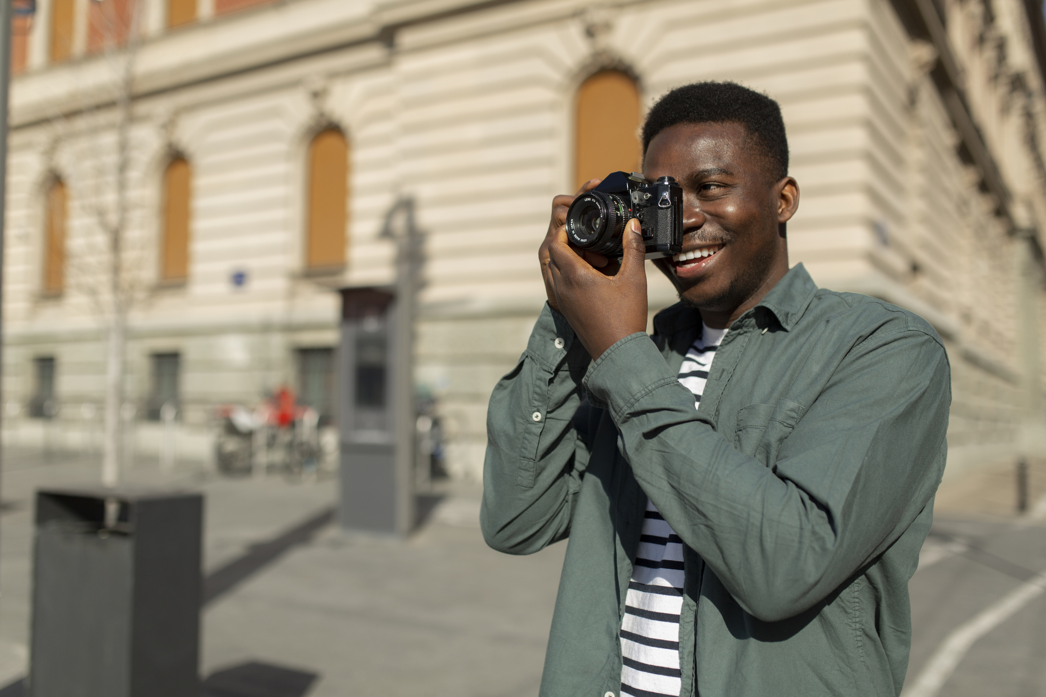 male photographer holding a photographic camera and taking photos in the city