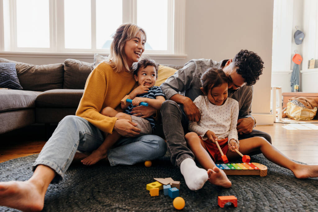 Young parents playing with their son and daughter in the living room.