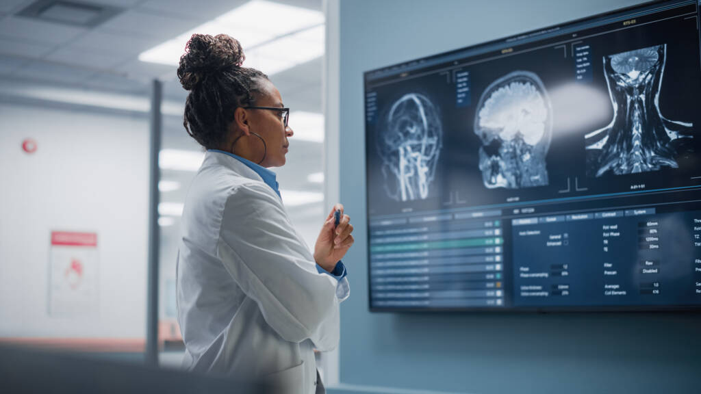 Neurologist, Neuroscientist, Neurosurgeon, Looks at TV Screen with MRI Scan with Brain Images, Thinks about Sick Patient Treatment Method. Saving Lives+