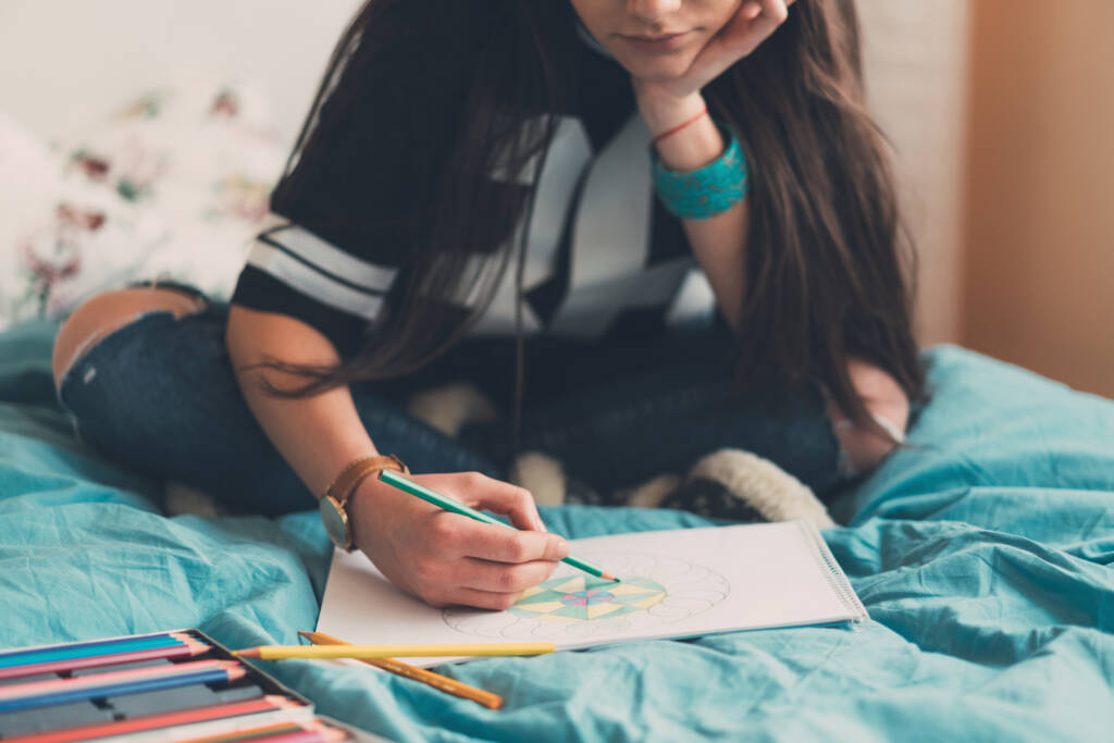 Young woman relaxing with anti-stress coloring book