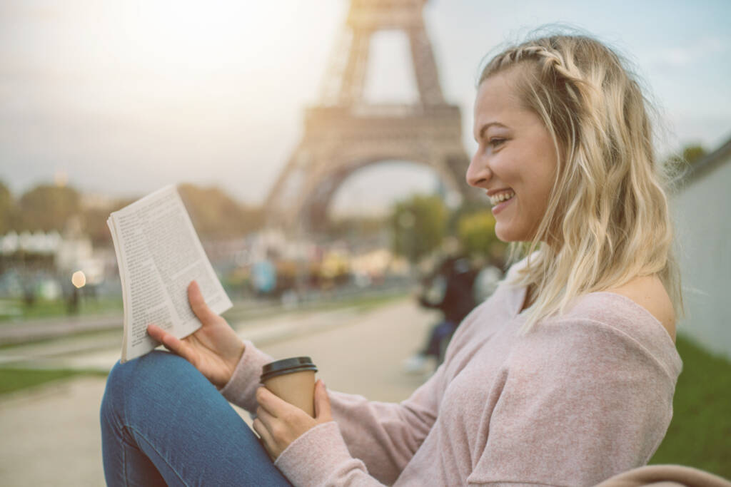 girl sitting on a bench in front of the Eiffel Tower in Paris, France and reading a book