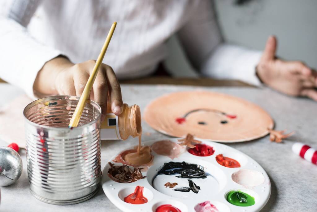 child pouring paint into a palette.