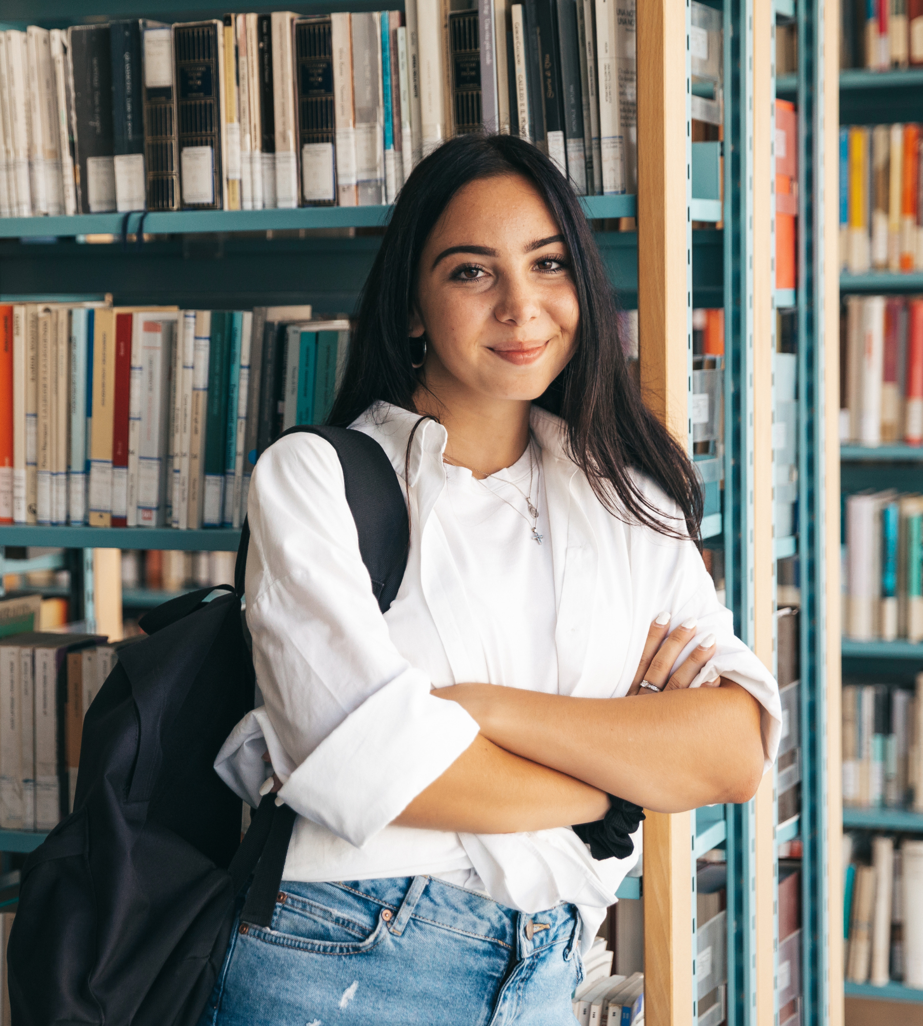 Female student leaning against bookcase.